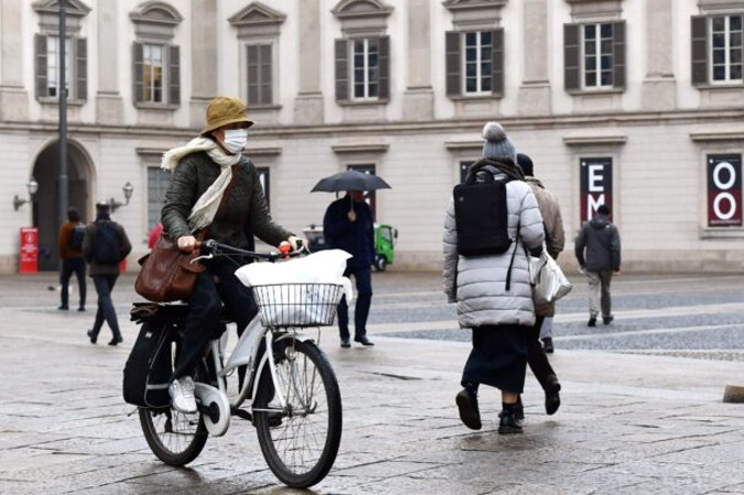 Kobieta w masce ochronnej przejeżdża rowerem przez Piazza del Duomo w Mediolanie, 2.03.2020 r.<br/>(Miguel Medina/AFP via Getty Images)