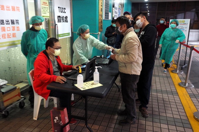 Pracownicy medyczni, niektórzy w odzieży ochronnej, sprawdzają Karty Ubezpieczenia Zdrowotnego, ang. Health Insurance Card, i pytają o historię podróży, zanim zezwolą na wejście do szpitala, Tajpej, Tajwan, 10.03.2020 r. (DAVID CHANG/PAP/EPA)