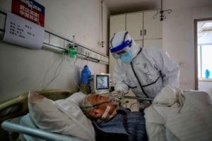 Członek personelu medycznego rozmawia z pacjentem zarażonym COVID-19 w szpitalu Czerwonego Krzyża, ang. Red Cross Hospital, w Wuhan, 10.03.2020 r. (STR/AFP via Getty Images)