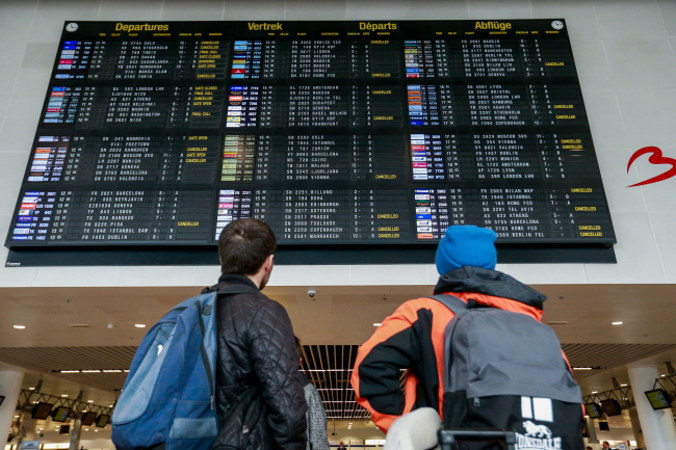 Podróżni patrzą na tablicę odlotów na lotnisku w Brukseli, Belgia, 15.03.2020 r. (STEPHANIE LECOCQ/PAP/EPA)