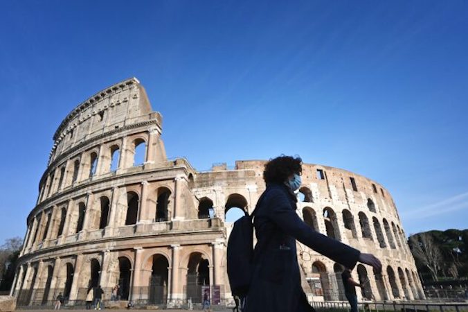 Turystka w maseczce, środku zapobiegającym rozprzestrzenianiu się koronawirusa COVID-19, przechodzi obok zamkniętego Koloseum w Rzymie, 10.03.2020 r., Włochy (Alberto Pizzoli/AFP via Getty Images)