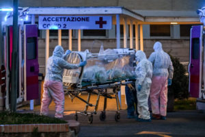 Pracownicy medyczni w kombinezonach zabierają pacjenta w stanie wymagającym intensywnej terapii do nowo wybudowanego szpitala tymczasowego Columbus Covid 2 w szpitalu Gemelli w Rzymie, 16.03.2020 r. (Andreas Solaro/AFP via Getty Images)