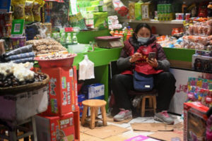 Ekspedientka korzysta z telefonu komórkowego, oczekując na klientów, Jiujiang, 6.03.2020 r.<br/>(NOEL CELIS/AFP via Getty Images)
