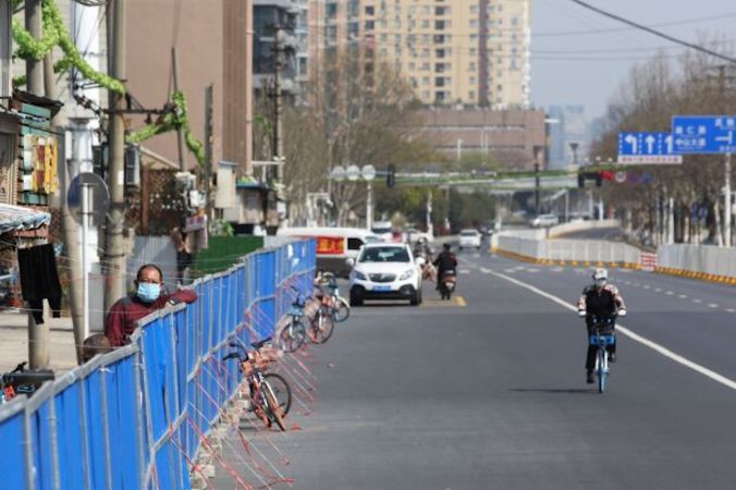 Mężczyzna wygląda przez barierę ustawioną, aby zapobiec wchodzeniu do osiedla mieszkaniowego lub jego opuszczaniu, Wuhan, 17.03.2020 r. (STR/AFP via Getty Images)