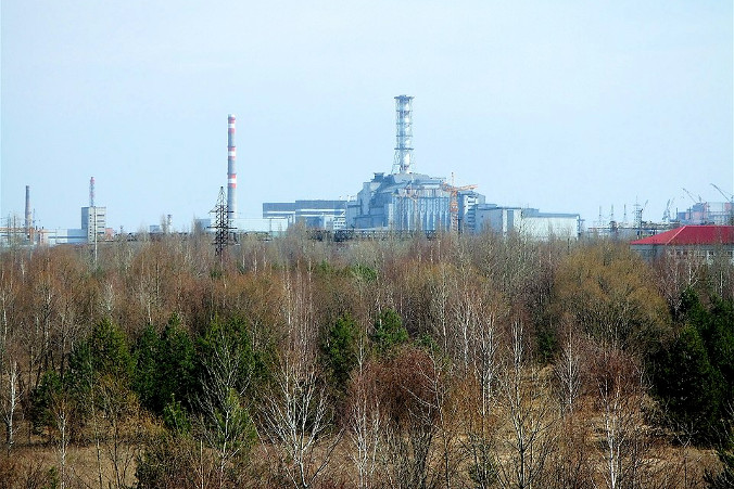 Elektrownia jądrowa w Czarnobylu, widziana z mostu na Prypeci, prawdopodobnie 2006 r. (Justin Stahlman z Montréalu, Kanada – <a href="https://www.flickr.com/photos/93823488@N00/457480382/">sarkofag w Czarnobylu</a>, <a href="https://creativecommons.org/licenses/by/2.0/">CC BY 2.0</a>, zdjęcie modyfikowane / <a href="https://commons.wikimedia.org/w/index.php?curid=7519059">Wikimedia</a>)