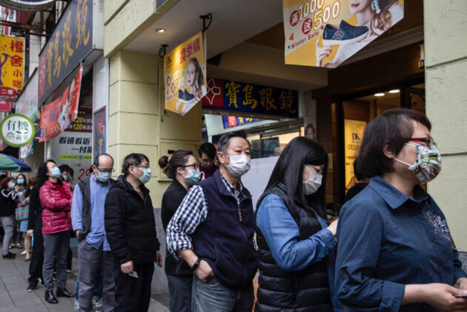 Ludzie czekają w aptece, aby odebrać maski, które wcześniej zamówili przez internet, 18.03.2020 r., Tajpej, Tajwan (Paula Bronstein / Getty Images)