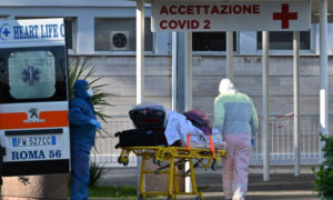 Pielęgniarze w maskach i kombinezonach ochronnych zabierają pacjenta na noszach do nowo wybudowanego szpitala tymczasowego Columbus COVID 2, szpital Gemelli w Rzymie, 16.03.2020 r. (Andreas Solaro/ AFP via Getty Images)