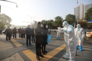 Pracownicy medyczni (ubrani w kombinezony ochronne) sprawdzają pacjentów, którzy wyzdrowieli z COVID-19 i przybyli na ponowne badania do szpitala, Wuhan, prowincja Hubei, Chiny, 14.03.2020 r. (STR/AFP/Getty Images)