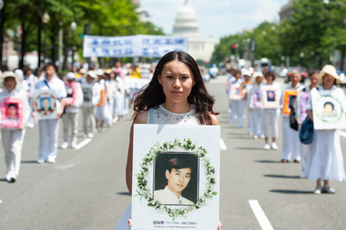 Kobieta trzyma fotografię mężczyzny zabitego przez chiński reżim w trakcie prześladowań Falun Gong, parada w Waszyngtonie, 17.06.2014 r. (Larry Dye / The Epoch Times)