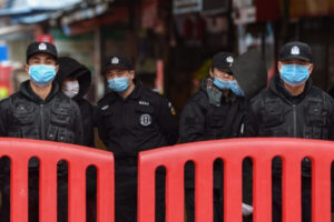 Funkcjonariusze policji i ochroniarze stoją przed targiem owoców morza Huanan w Wuhan, gdzie wirus KPCh został wykryty, 24.01.2020 r. (Hector Retamal/AFP via Getty Images)