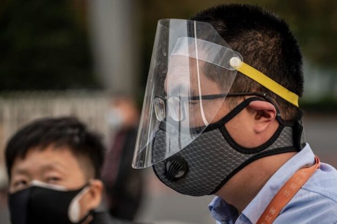 Mężczyzna w masce i przyłbicy w drodze do pracy w godzinach szczytu, Pekin, 7.04.2020 r.<br /> (Nicolas Asfouri/AFP via Getty Images)