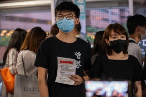Działacz na rzecz demokracji i przywódca partii Demosistō Joshua Wong (po lewej) rozdaje ulotki przeciwko projektowanemu chińskiemu prawu o bezpieczeństwie narodowym, Hongkong, 22.05.2020 r. (JEROME FAVRE/PAP/EPA)