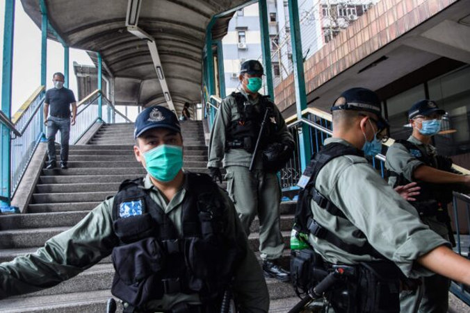 Policja tworzy kordon w pobliżu protestujących na rzecz demokracji (niewidocznych na zdjęciu) podczas ich przemarszu sprzed Western Police Station do biura łącznikowego, czyli przedstawicielstwa chińskich władz, Hongkong, 22.05.2020 r. (Anthony Wallace/AFP via Getty Images)