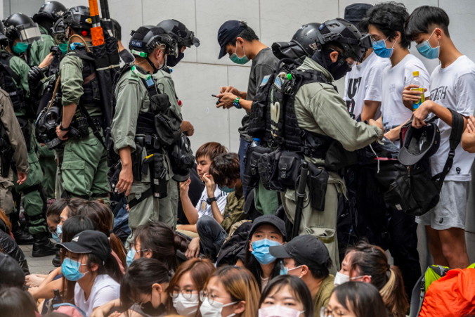 Policjanci przeszukują torby i sprawdzają smartfony zatrzymanych, kordon policyjny w okolicy Causeway Bay, Hongkong, 27.05.2020 r. (MIGUEL CANDELA/PAP/EPA)