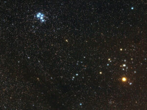 Plejady, u góry po lewej, i Hiady w prawym dolnym rogu. Na ich tle widoczny Aldebaran, pomarańczowy gigant w prawym dolnym rogu. W prawym górnym rogu znajduje się gwiazda λ Tauri. Gromada otwarta NGC 1647 jest również rozpoznawalna w pobliżu dolnej krawędzi zdjęcia (Giuseppe Donatiello – Hiady i Plejady, CC0 / <a href="https://commons.wikimedia.org/w/index.php?curid=62037050">Wikimedia</a>) 