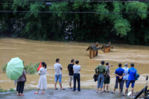 Ludzie oglądają zatopioną ulicę w powiecie Rongan, prowincja Guangxi, południowy region Chin, 10.06.2020 r. (STR/AFP via Getty Images)