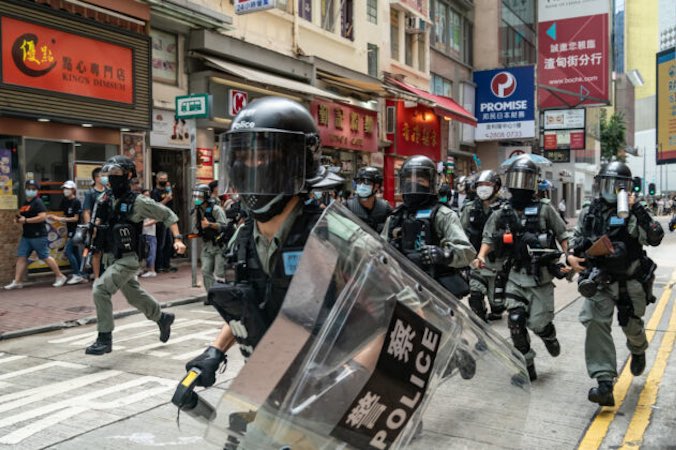 Policyjny oddział prewencyjny biegnie ulicą w kierunku pieszych podczas akcji kontroli tłumu w trakcie demonstracji w Hongkongu, 1.07.2020 r. (Anthony Kwan / Getty Images)