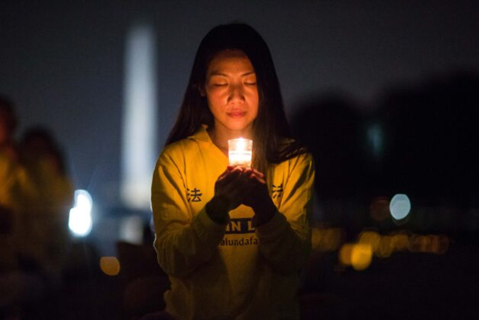 Kobieta dołącza do praktykujących Falun Gong, którzy czuwają przy świecach pod pomnikiem Lincolna w Waszyngtonie 20.07.2017 r., aby uczcić tych, którzy zginęli podczas prześladowań w Chinach, zapoczątkowanych przez chiński reżim 20.07.1999 r. (Benjamin Chasteen / The Epoch Times)