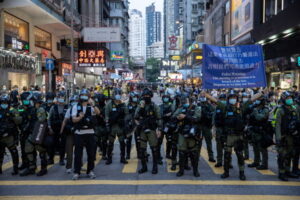 Funkcjonariusz policji podnosi transparent ostrzegający demonstrantów, że zgromadzenie narusza prawo oraz że policja może użyć siły, jeśli protestujący się nie rozejdą, wiec przeciwko przełożeniu wyborów do Rady Legislacyjnej, Hongkong, 6.09.2020 r. (JEROME FAVRE/PAP/EPA)