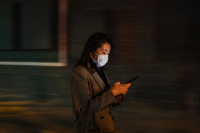 Kobieta sprawdza swój telefon komórkowy w Szanghaju, Chiny, 17.03.2020 r.<br/>(HECTOR RETAMAL/AFP via Getty Images)