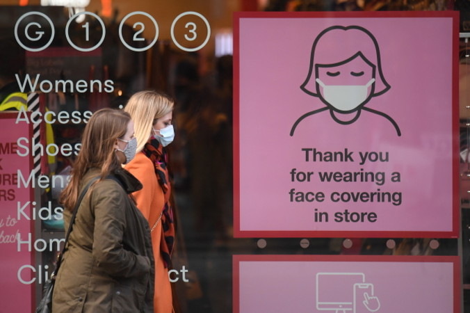 Przechodnie w maseczkach na twarzy mijają informacje ostrzegające przed COVID-19, Oxford Street w Londynie, Wielka Brytania, 1.10 2020 r. (NEIL HALL/PAP/EPA)