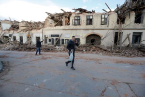 Mężczyźni przechodzą obok budynków uszkodzonych podczas trzęsienia ziemi w Petrinji w Chorwacji, 29.12.2020 r. (ANTONIO BAT/PAP/EPA)
