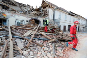 Ratownicy sprawdzają budynki uszkodzone w wyniku trzęsienia ziemi w mieście Petrinja, Chorwacja, 29.12.2020 r. (ANTONIO BAT/PAP/EPA)
