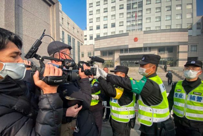 Policja próbuje powstrzymać dziennikarzy przed nagrywaniem materiału filmowego przed Sądem Ludowym Nowej Dzielnicy Pudong w Szanghaju, w którym wydano wyrok w sprawie dziennikarki obywatelskiej Zhang Zhan, Szanghaj, Chiny, 28.12.2020 r. (Leo Ramirez / AFP via Getty Images)