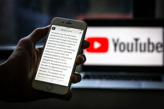 Ogłoszenie YouTube o tym, że firma natychmiast zacznie usuwać treści zarzucające „powszechne oszustwa lub błędy” w tegorocznych wyborach prezydenckich, wyświetlone na telefonie 9.12.2020 r.<br/>(Samira Bouaou / The Epoch Times)