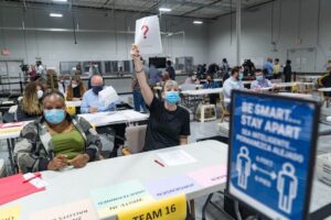 Pracownica z hrabstwa Gwinnett podnosi kartkę papieru, dając znak, że ma pytanie podczas przeliczania głosów w Lawrenceville, Georgia, 13.11.2020 r. (Megan Varner / Getty Images)