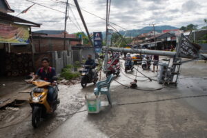Motorowerzyści przejeżdżają obok słupa elektrycznego zniszczonego w następstwie trzęsienia ziemi, Mamuju, Celebes Zachodni, Indonezja, 16.01.2021 r. (OPAN BUSTAN/PAP/EPA)