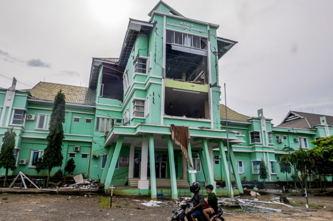 Motorowerzyści przejeżdżają obok szpitala uszkodzonego na skutek trzęsienia ziemi o sile 6,2 st., Mamuju, Celebes Zachodni, Indonezja, 17.01.2021 r. (IQBAL LUBIS/PAP/EPA)