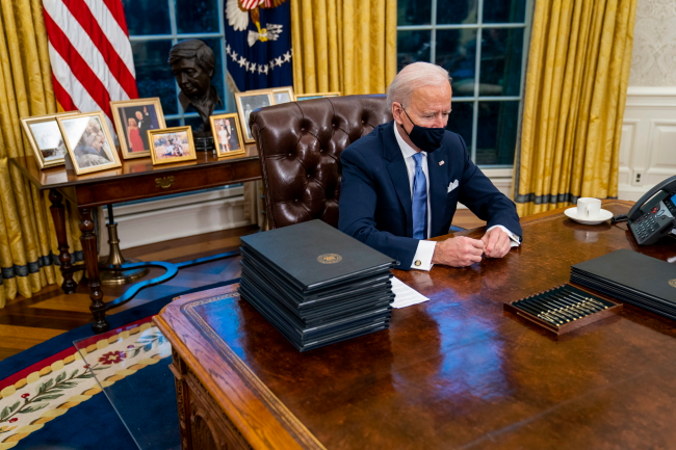 Prezydent USA Joe Biden podpisuje rozporządzenia wykonawcze podczas pierwszych minut w Gabinecie Owalnym w Białym Domu, Waszyngton, 20.01.2021 r. (Doug Mills/POOL/PAP/EPA)