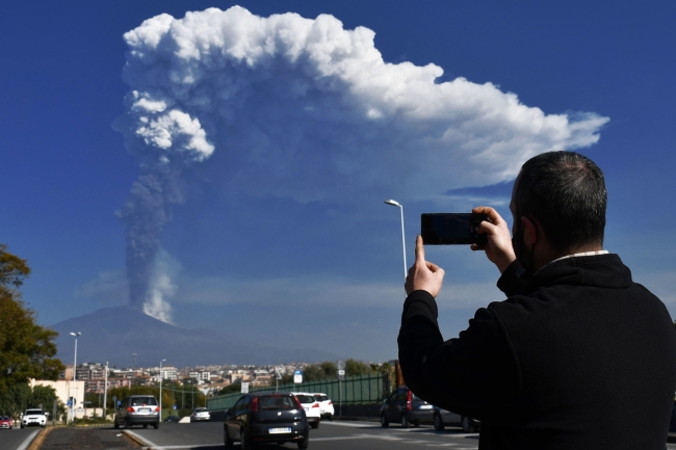 Mężczyzna robi zdjęcie wybuchu południowo-wschodniego krateru Etny z Katanii we Włoszech, 4.03.2021 r. (ORIETTA SCARDINO/PAP/EPA)