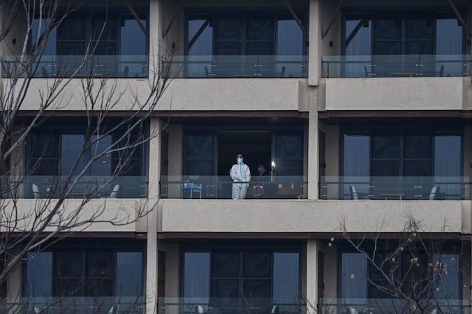 Pracownik służby zdrowia czeka na balkonie na członków zespołu ekspertów Światowej Organizacji Zdrowia, WHO, którzy mają zbadać pochodzenie COVID-19, hotel Hilton Wuhan Optics Valley, Wuhan w prowincji Hubei, środkowe Chiny, 6.02.2021 r. (Hector Retamal/AFP via Getty Images)