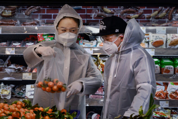 Para w płaszczach foliowych i maskach ochronnych robi zakupy spożywcze w supermarkecie w Pekinie, Chiny, 11.02.2020 r. (Kevin Frayer / Getty Images)