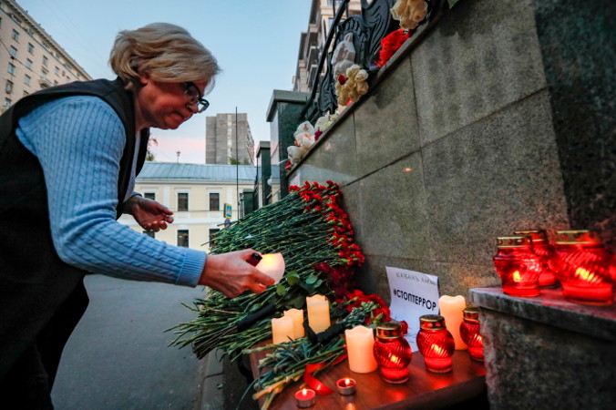 Kobieta zapala świecę pod spontanicznym pomnikiem przy Stałym Przedstawicielstwie Tatarstanu w Moskwie po strzelaninie w Kazaniu, Rosja, 11.05.2021 r. (YURI KOCHETKOV/PAP/EPA)