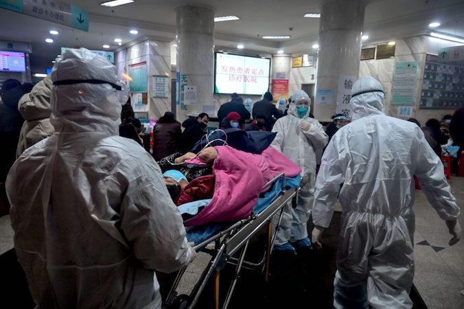 Personel medyczny w odzieży ochronnej przybywa z pacjentem do szpitala Czerwonego Krzyża w Wuhan, prowincja Hubei, Chiny, 25.01.2020 r. (Hector Retamal/AFP via Getty Images)
