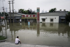 Mieszkaniec Wuhan siedzi przy zalanym parku Jiangtan nad rzeką Jangcy, Wuhan, Chiny, 10.07.2020 r. (Getty Images)