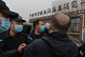 Pracownicy ochrony stoją obok członków delegacji Światowej Organizacji Zdrowia, WHO, która przybyła do Wuhańskiego Instytutu Wirusologii, by zbadać pochodzenie COVID-19, Wuhan, Chiny, 3.02.2021 r. (Hector Retamal/AFP via Getty Images)