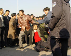 Dwóch ubranych po cywilnemu policjantów aresztowało praktykującego Falun Gong na placu Tiananmen w Pekinie, 31.12.2000 r. (Minghui.org)