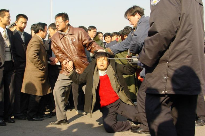 Dwóch ubranych po cywilnemu policjantów aresztowało praktykującego Falun Gong na placu Tiananmen w Pekinie, 31.12.2000 r. (Minghui.org)