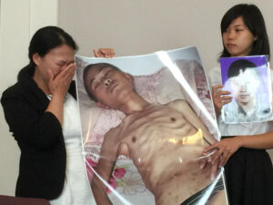 Praktykująca Falun Gong pani Chi Lihua i jej córka Xu Xinyang prezentują zdjęcia Xu Dawei, swojego męża i taty, zdjęcia „przed torturami i po torturach”. Gdy pani Chi Lihua była w ciąży, jej mąż za praktykowanie Falun Gong został skazany na 8 lat. Gdy został wypuszczony, córka mogła spędzić z ojcem zaledwie 13 dni, nim zmarł z powodu obrażeń, których doznał na skutek tortur w więzieniu. Xu Xinyang ma teraz 16 lat (Jennifer Zeng / The Epoch Times)