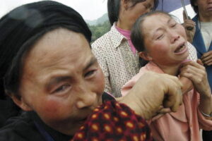 Członkowie rodziny płaczą podczas pogrzebu ofiary, która zginęła w wyniku zawalenia się zbiornika wodnego w powiecie Yiliang w prowincji Yunnan, południowo-zachodnie Chiny, 22.07.2005 r. (China Photos / Getty Images)