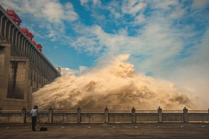 Fotograf wykonuje zdjęcia, gdy z Zapory Trzech Przełomów, gigantycznego projektu hydroenergetycznego na rzece Jangcy, spuszczana jest woda, aby zmniejszyć poziom wody powodziowej w Yichang, prowincja Hubei, środkowe Chiny, 19.07.2020 r. (STR/AFP via Getty Images)