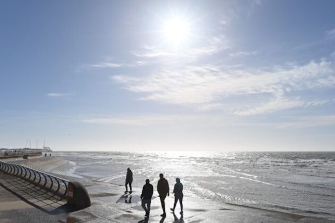 Ludzie cieszą się słońcem, spacerując wzdłuż plaży w Blackpool, Lancashire, Wielka Brytania, 16.03.2021 r. (Paul Ellis/AFP via Getty Images)