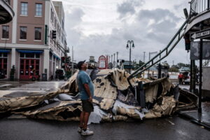Mężczyzna patrzy w górę na kawałek dachu, który oderwał się od budynku w Dzielnicy Francuskiej, ang. French Quarter, na skutek huraganu Ida, Nowy Orlean, Luizjana, USA, 30.08.2021 r. (DAN ANDERSON/PAP/EPA)