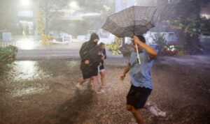 Ludzie poruszają się w ulewnym deszczu po zalanych chodnikach w Billie Jean King National Tennis Center, gdy pozostałości huraganu Ida uderzyły w okolicę, Flushing Meadows w Nowym Jorku, 1.09.2021 r. (JUSTIN LANE/PAP/EPA)