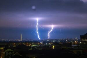 Kapitol USA (po prawej) i Pomnik Waszyngtona (po lewej) widoczne w świetle błyskawic podczas silnej burzy w Waszyngtonie, DC, obserwowane z Arlington, Wirginia, USA, 1.09.2021 r. (GAMAL DIAB/PAP/EPA)