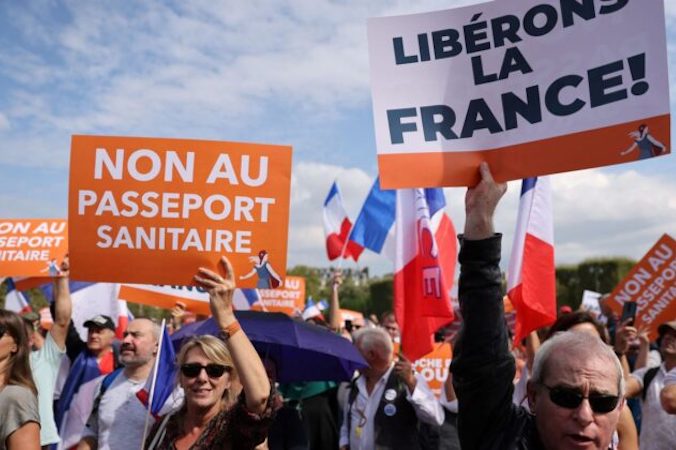 Ludzie trzymają transparenty z napisami „nie dla przepustek sanitarnych” (po lewej) i „wyzwólmy Francję” podczas demonstracji w Paryżu, 4.09.2021 r. (THOMAS COEX/AFP via Getty Images)